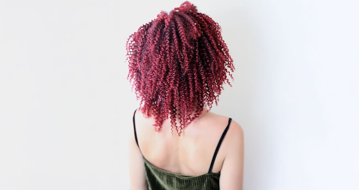 Cabelo crespo vermelho cereja em penteado volumoso visto de costas